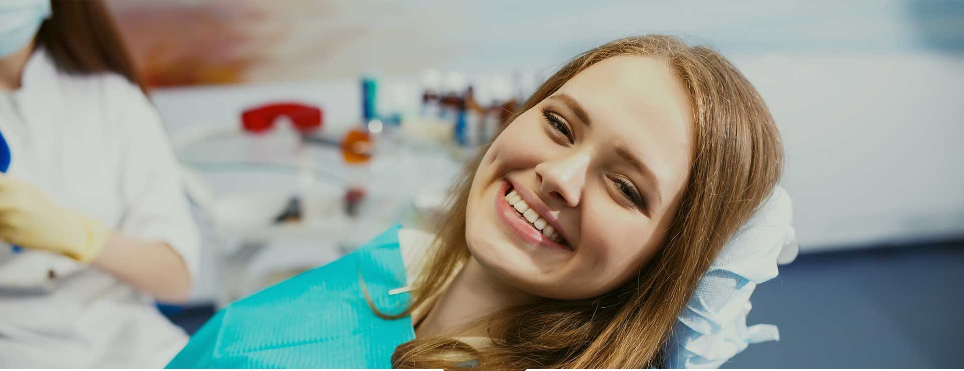Smiling patient sitting comfortably in a dental chair, representing successful tooth replacement and improved confidence through dental implants.